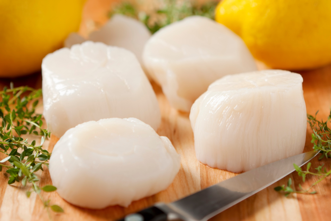 Raw scallops on cutting board